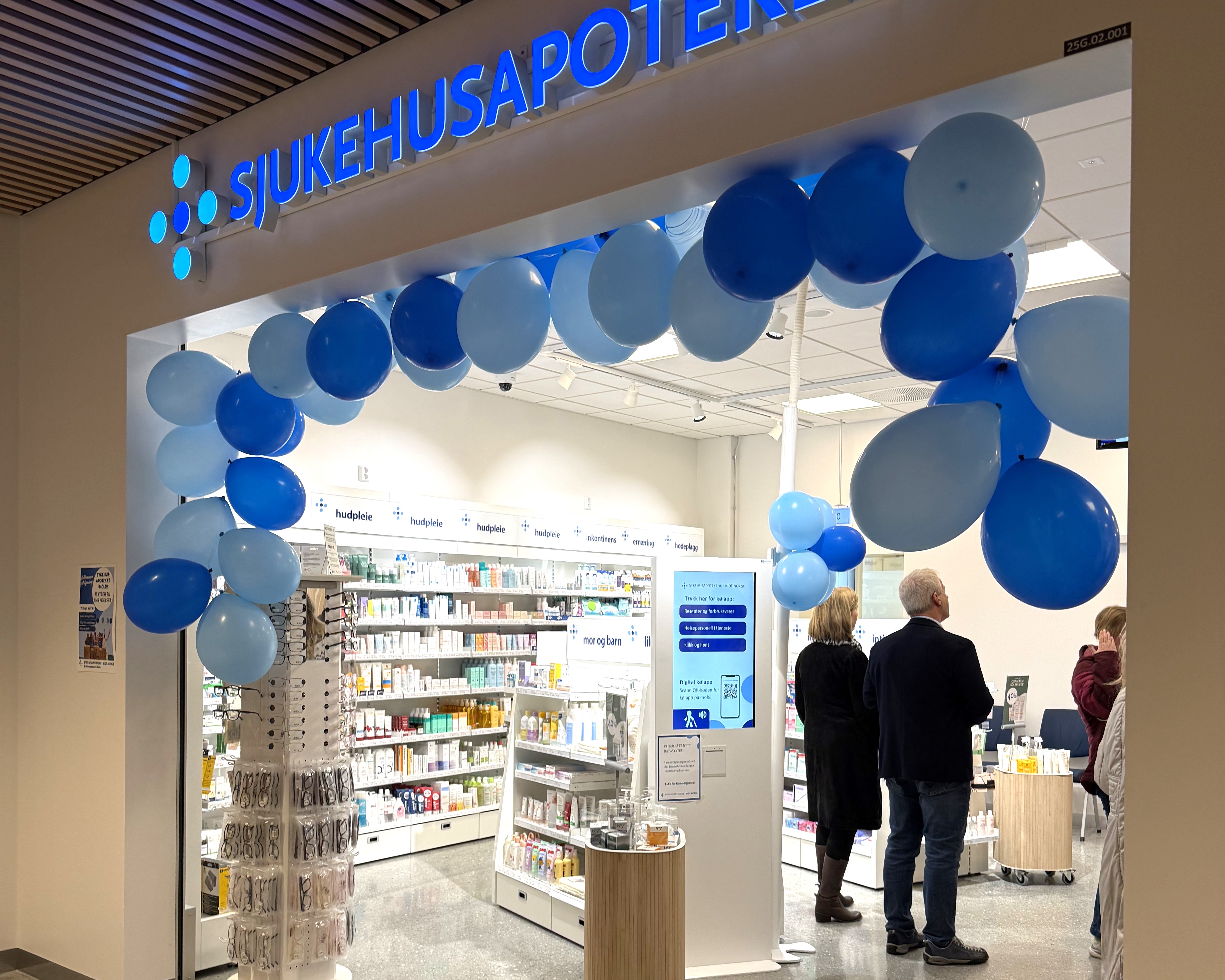 En gruppe mennesker som står i en bygning med blå ballonger